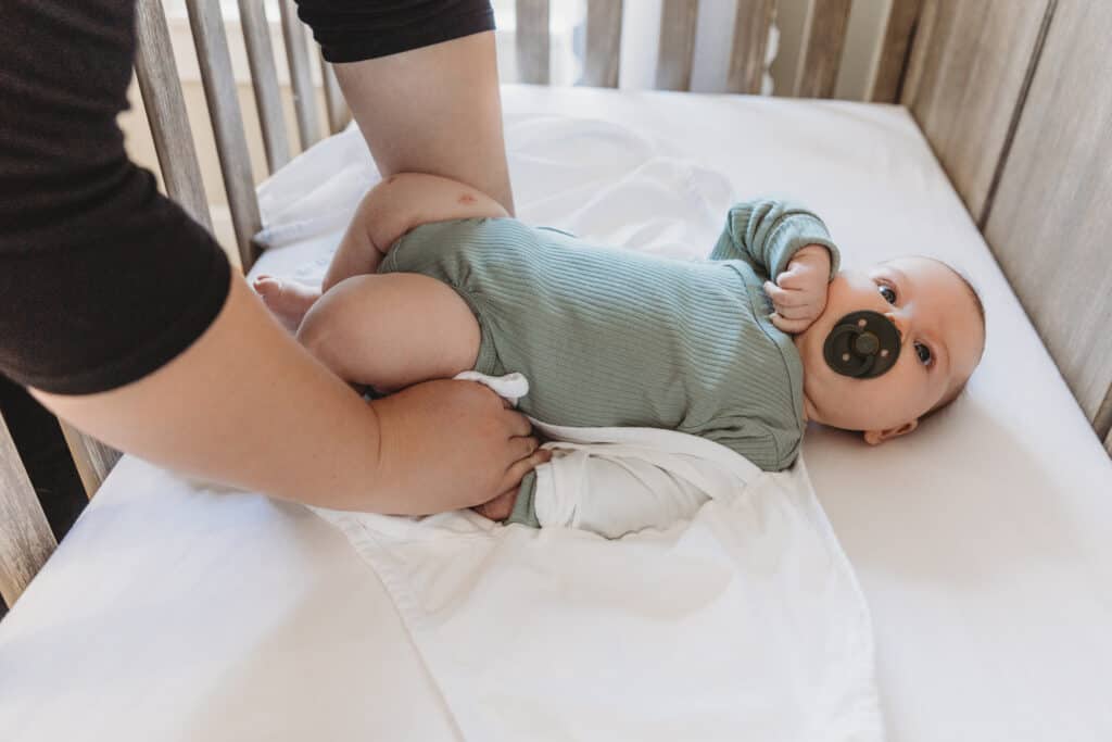 baby in crib being swaddled with miracle blanket
