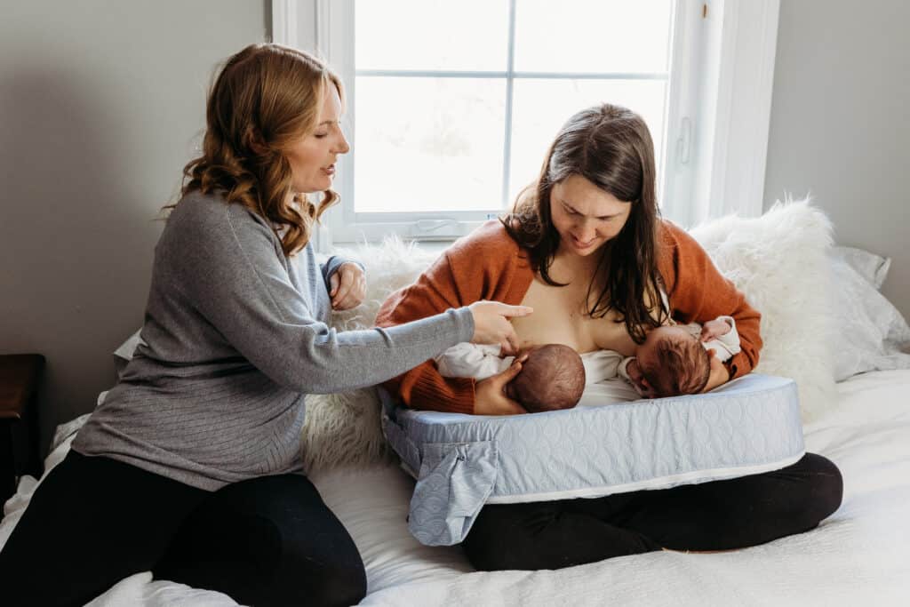 mom feeding twins with nursing pillow and doula helping