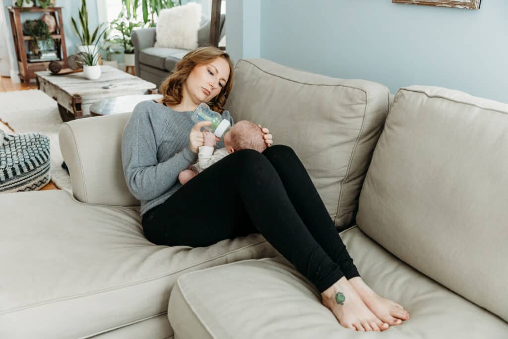 Mom feeding newborn with bottle on couch