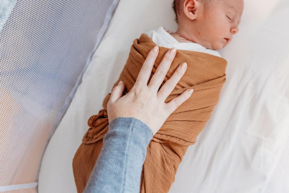 Newborn baby swaddled asleep in bassinet