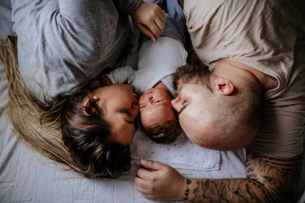 Two parents snuggling with newborn baby