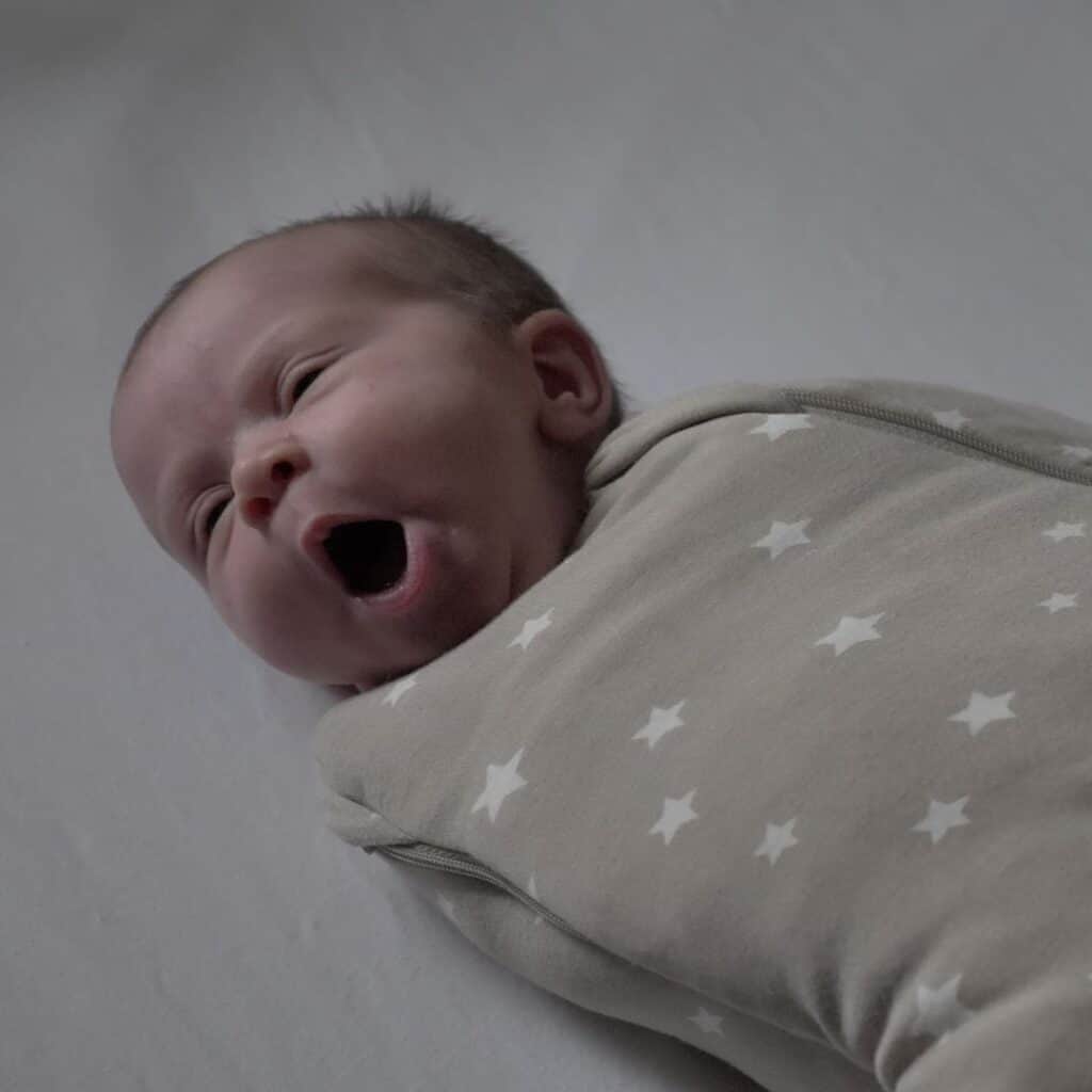 Sleepy newborn baby swaddled and yawning
